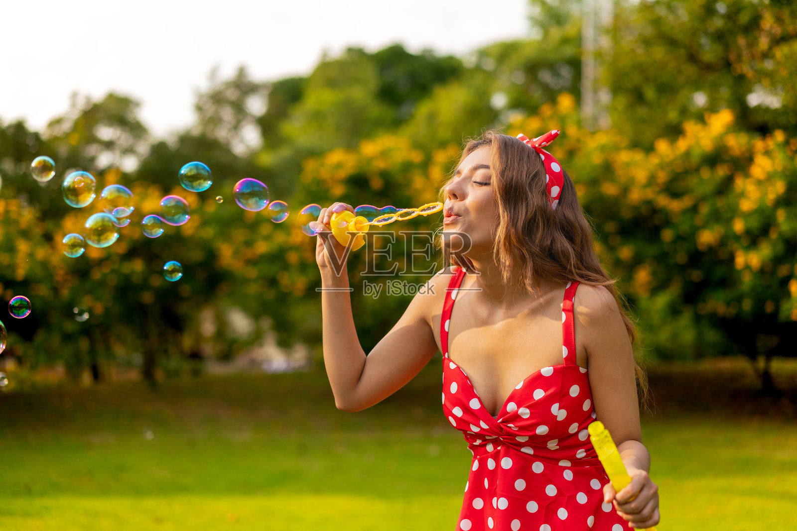 年轻女性穿着复古波点裙在公园户外吹泡泡照片摄影图片