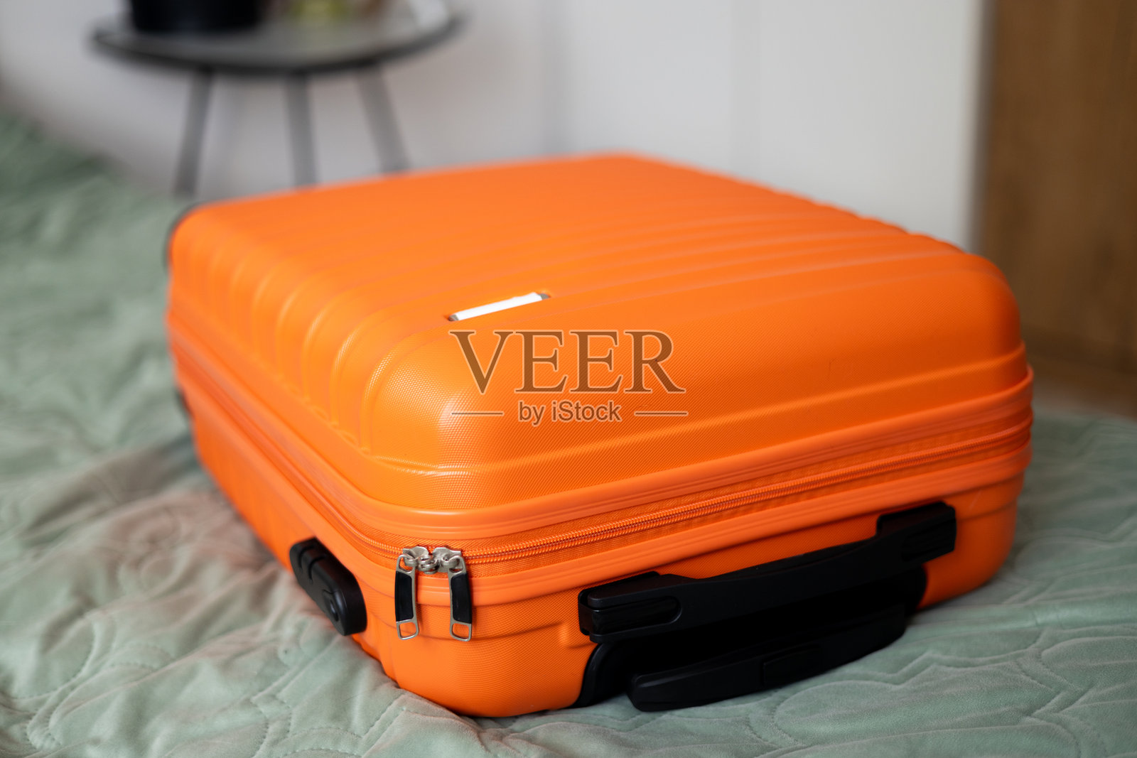 明亮房间里的大橙色行李箱放在床上。行李箱正在打包，准备去旅行度假。生活方式、冒险和旅游概念。照片摄影图片
