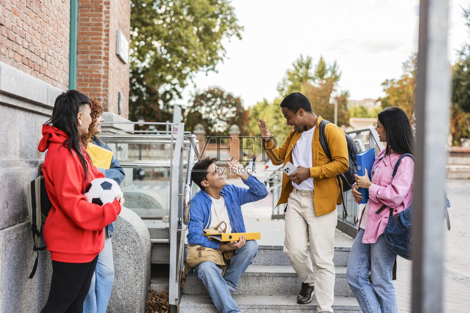 快乐的学生在大学校园里击掌庆祝照片摄影图片