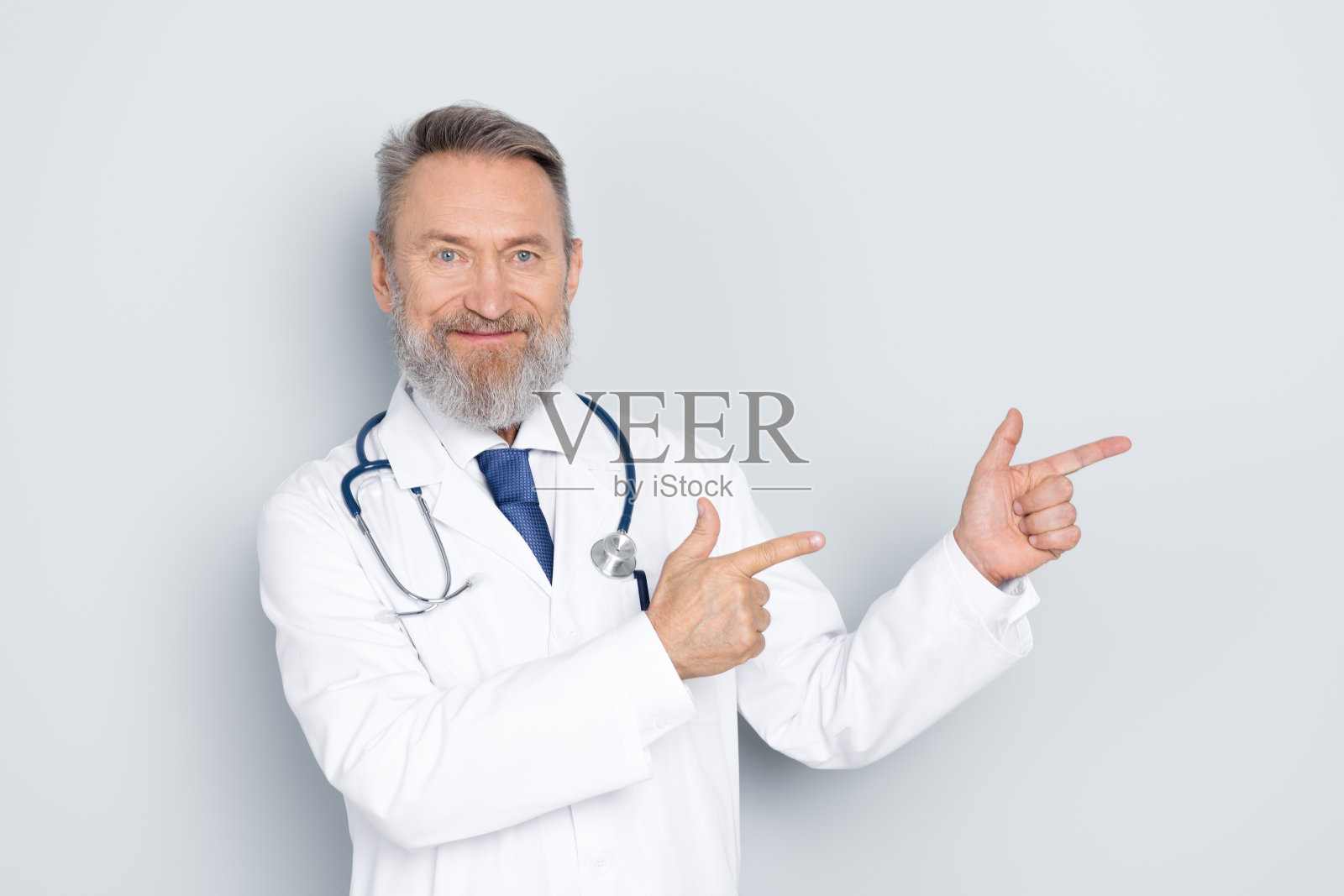 微笑着指向空白处的老年男性医生肖像照片摄影图片