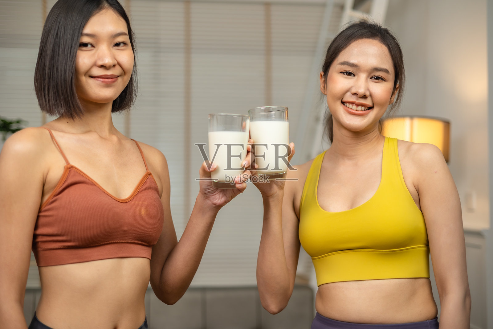 年轻的亚洲运动女性在家中的客厅喝蛋白质奶昔。照片摄影图片