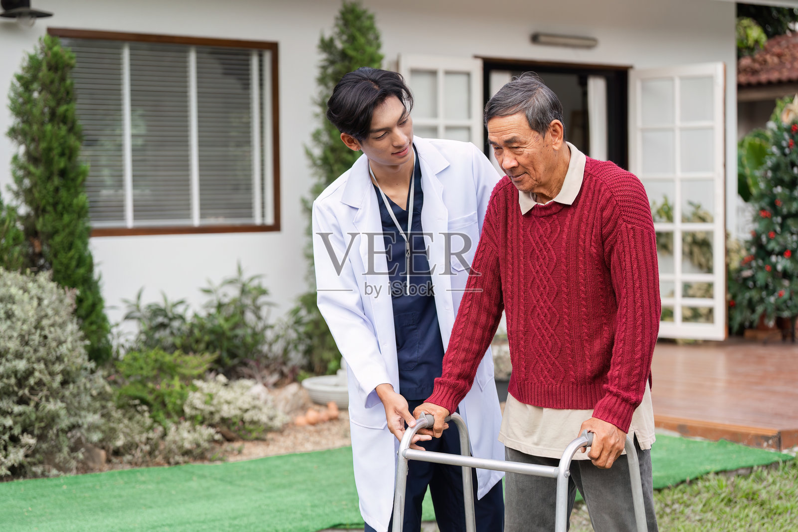 医疗专业人员在宁静的花园环境中协助使用助行器的老年男性照片摄影图片