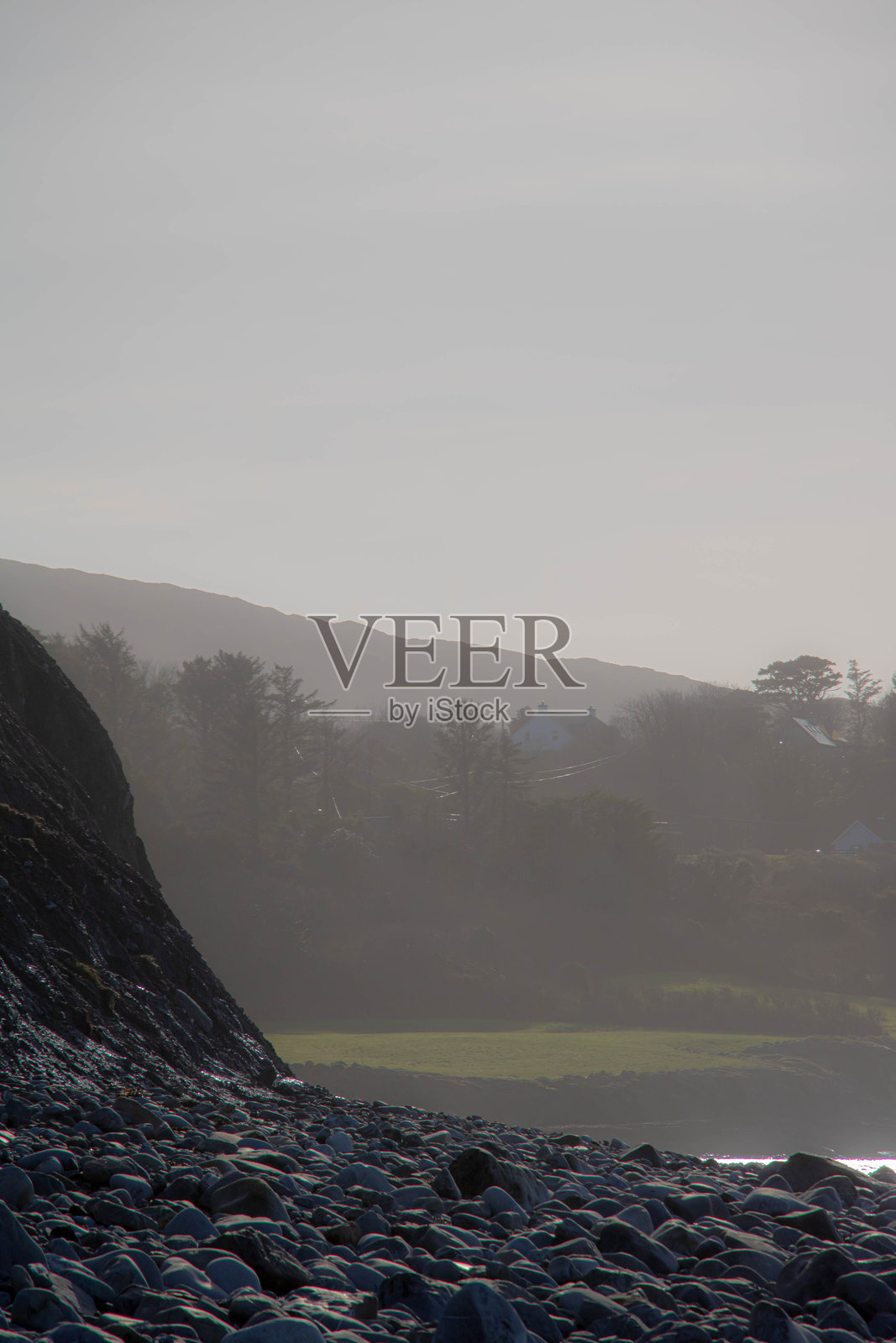 阳光下的雾景，前景散落着石头，呈垂直构图。照片摄影图片