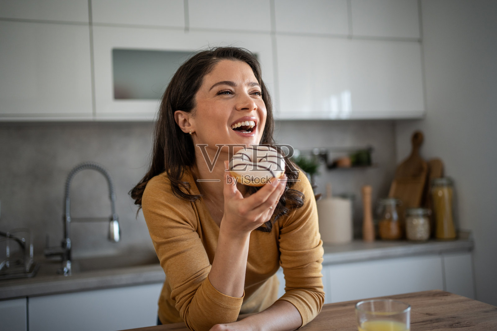 快乐的女人在家中放松时享受甜甜圈照片摄影图片