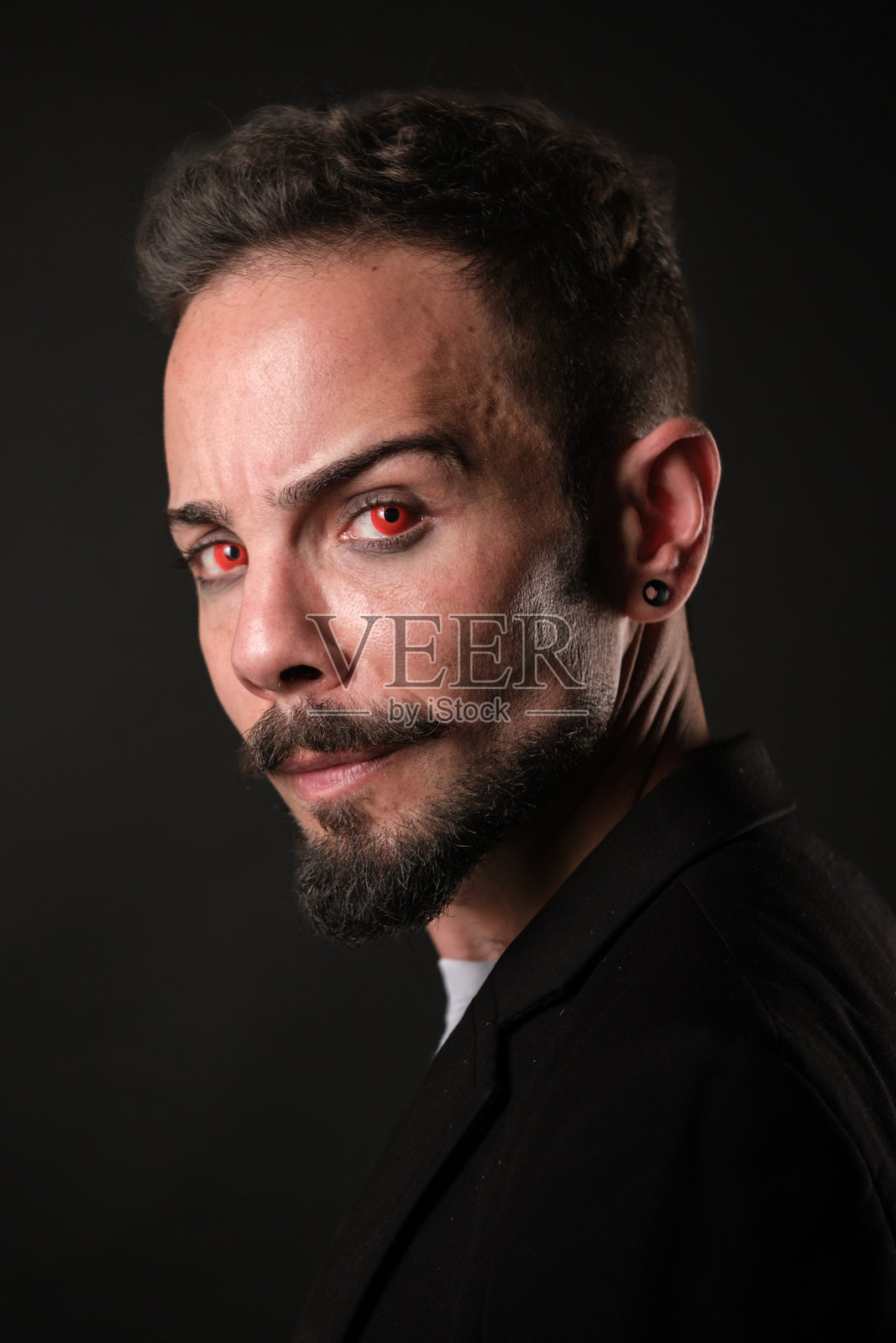 神秘的红眼男子在昏暗的环境中，佩戴红色隐形眼镜照片摄影图片