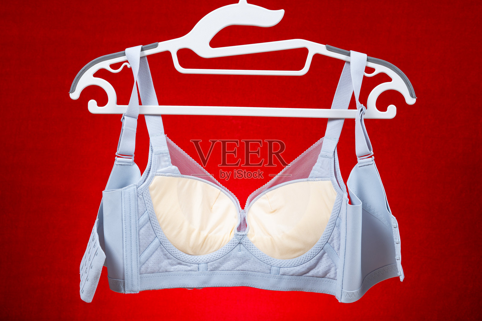 浅蓝色文胸挂在红色背景上照片摄影图片