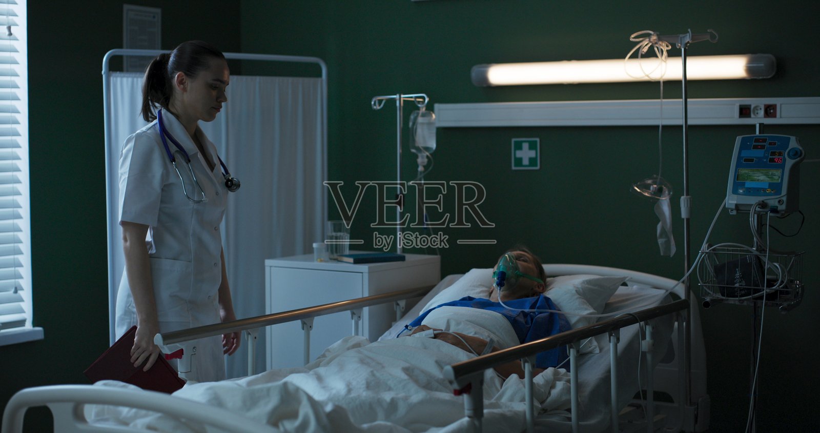 年长患者躺在医院病房里，佩戴着氧气面罩，努力恢复手术后的体力。照片摄影图片