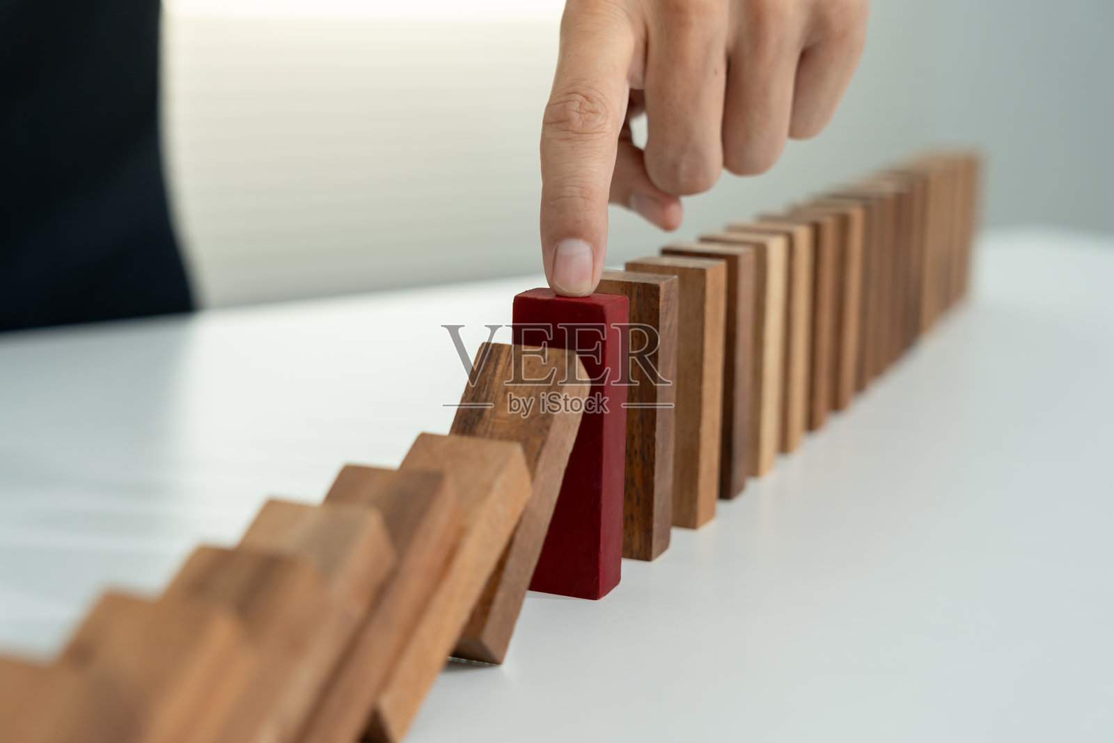 保险与手保护多米诺骨牌。商人用手阻止多米诺骨牌在商业危机中倒下。商业风险控制、规划和策略以防止保险业务的损失。照片摄影图片