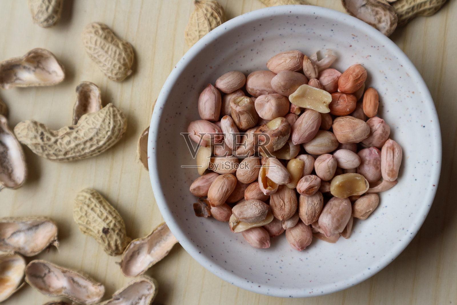 木桌上的碗里装着花生照片摄影图片