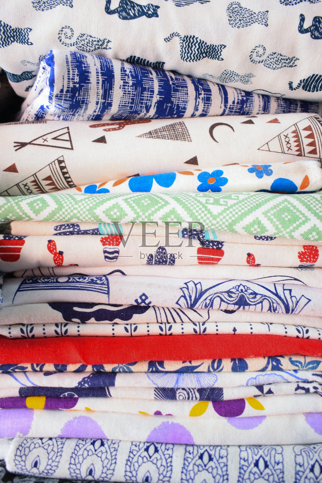 商店货架上出售的五颜六色的布料堆。照片摄影图片