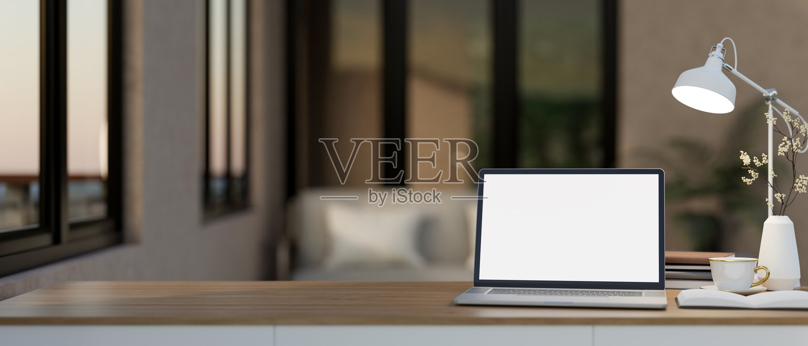 一台白色屏幕的笔记本电脑放在木桌上，旁边有装饰物，营造出温馨的工作空间。照片摄影图片