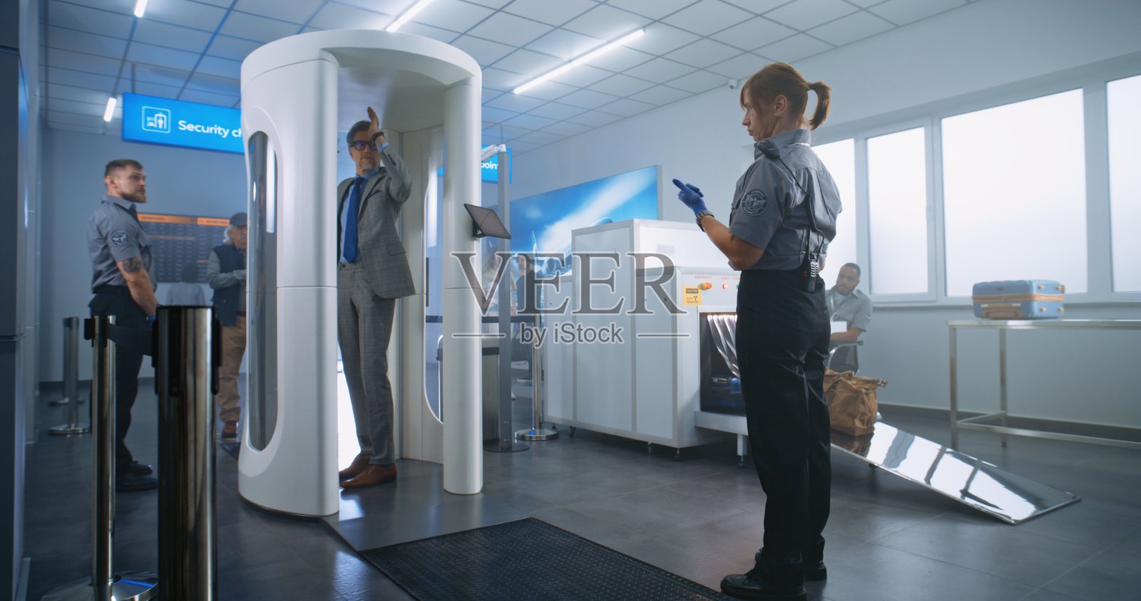 机场航站楼安检：不同种族的人们走过金属探测门照片摄影图片