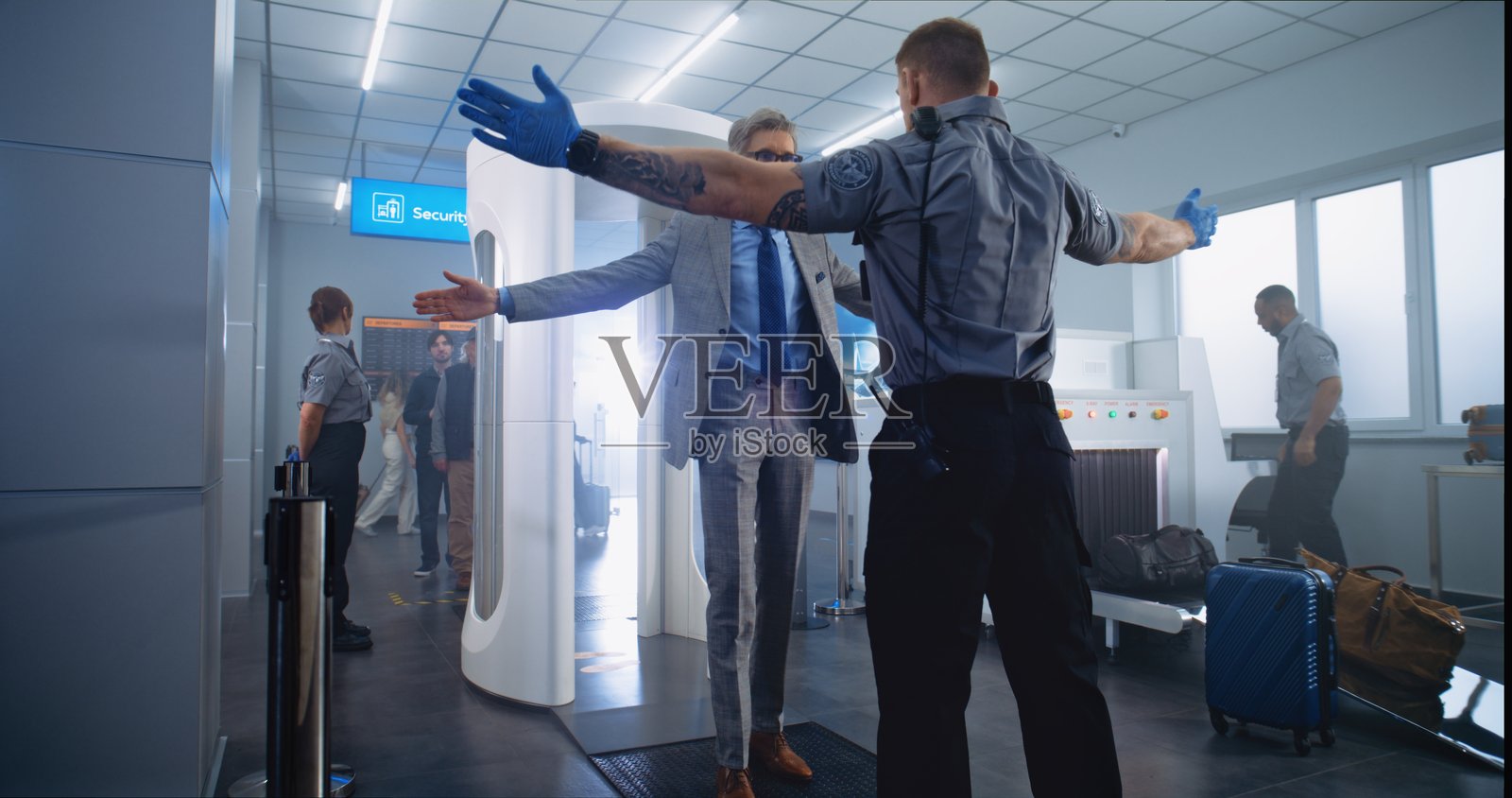 成熟男性通过金属探测器扫描仪。安保人员检查乘客以便登机。照片摄影图片