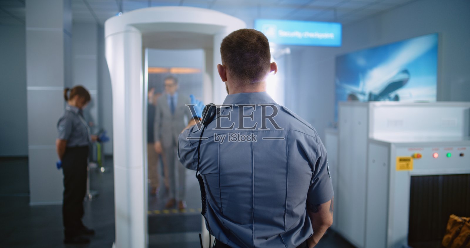 成熟男性走过金属探测门。安保人员检查乘客及其文件。照片摄影图片