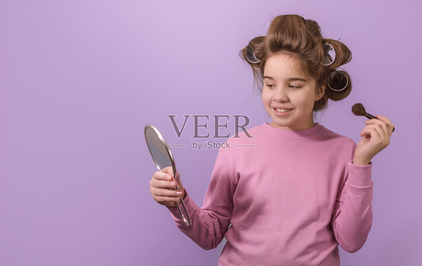 一个小女孩站在镜子前，梳理她的头发。照片摄影图片