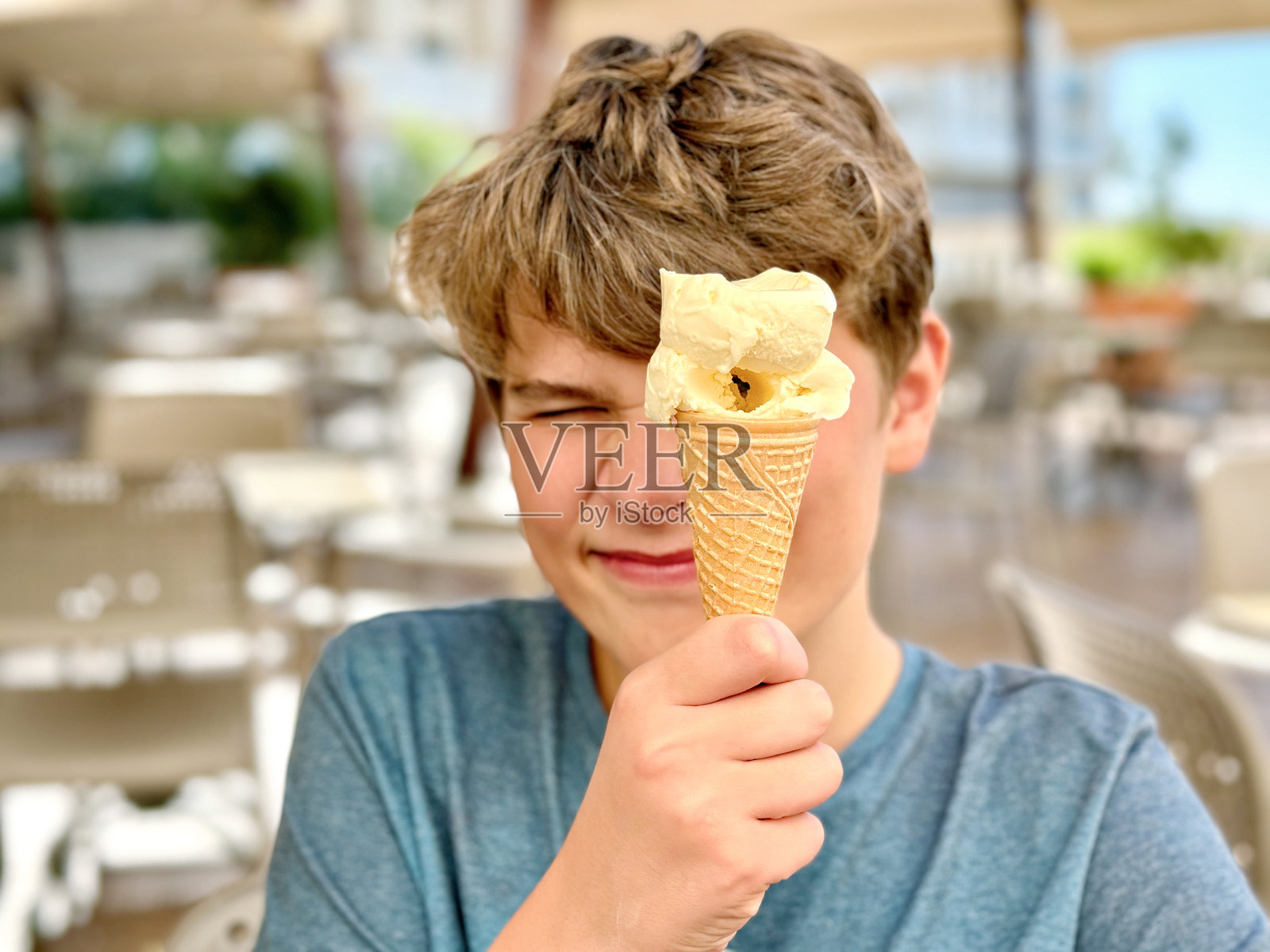 快乐的预青少年男孩在华夫筒里吃五彩冰淇淋，欢笑不已。在夏季炎热中感到凉爽。孩子们的甜点。快乐的孩子。照片摄影图片