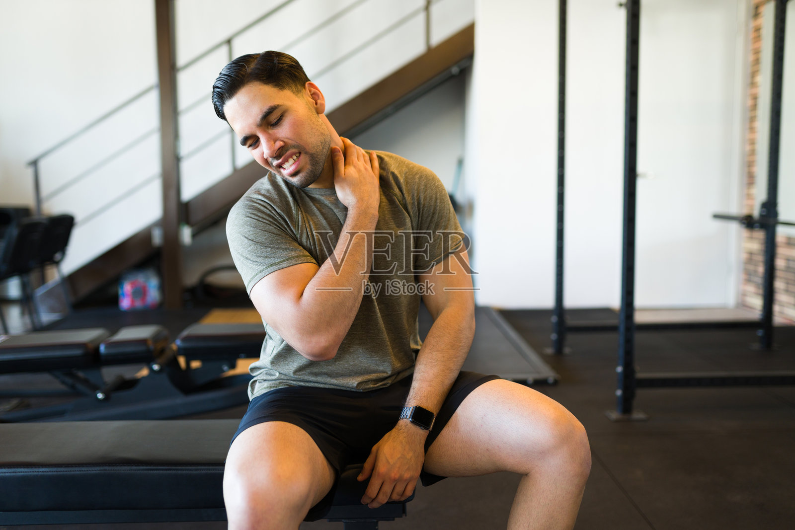 拉丁运动员在健身中心进行激烈锻炼后，感到脖子肌肉痉挛和不适。照片摄影图片