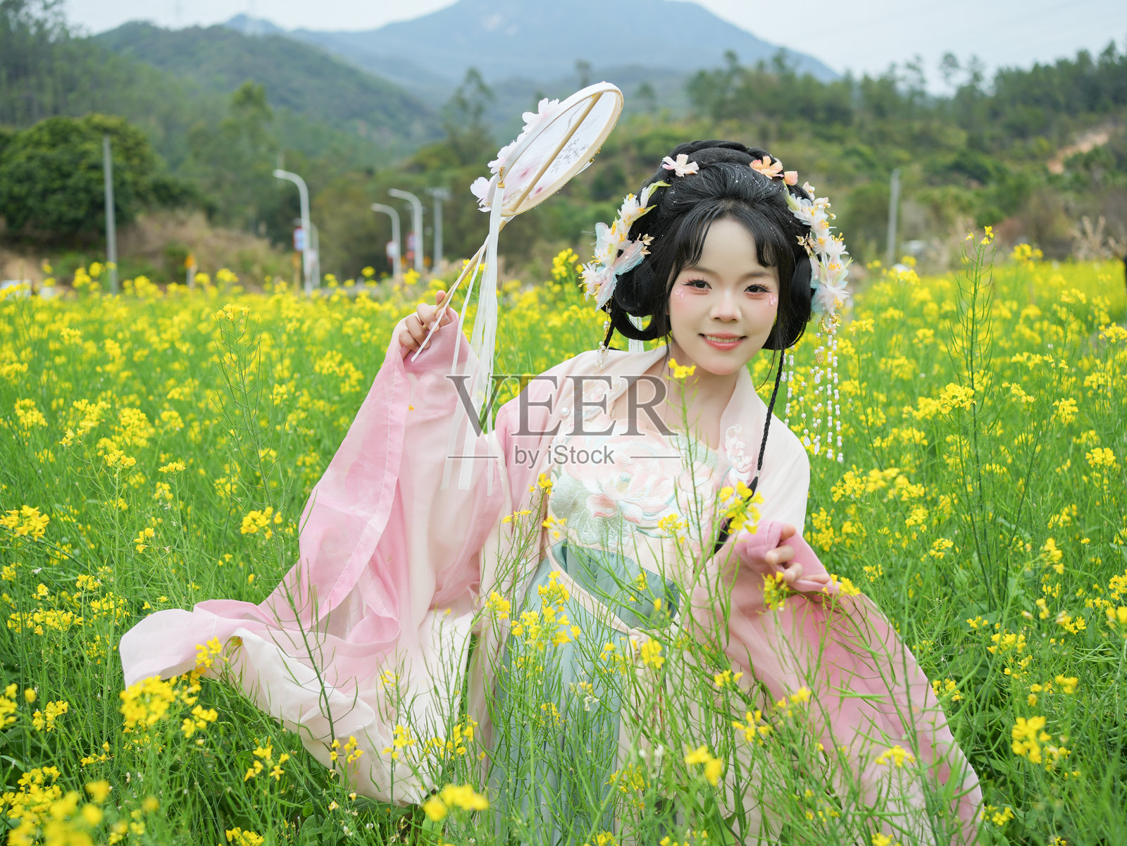 游客穿着汉服在油菜花海中照片摄影图片