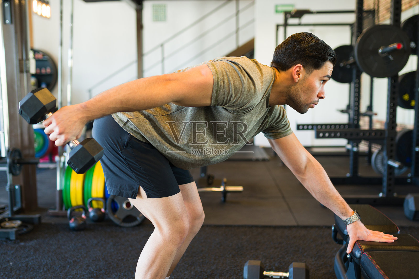 肌肉健身爱好者在现代健身设施中进行力量训练，使用重型器械进行锻炼照片摄影图片