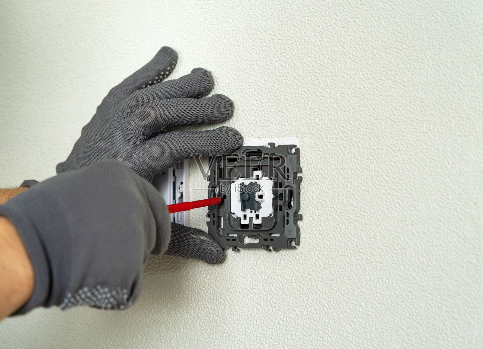 电工用螺丝刀安装电灯开关。照片摄影图片