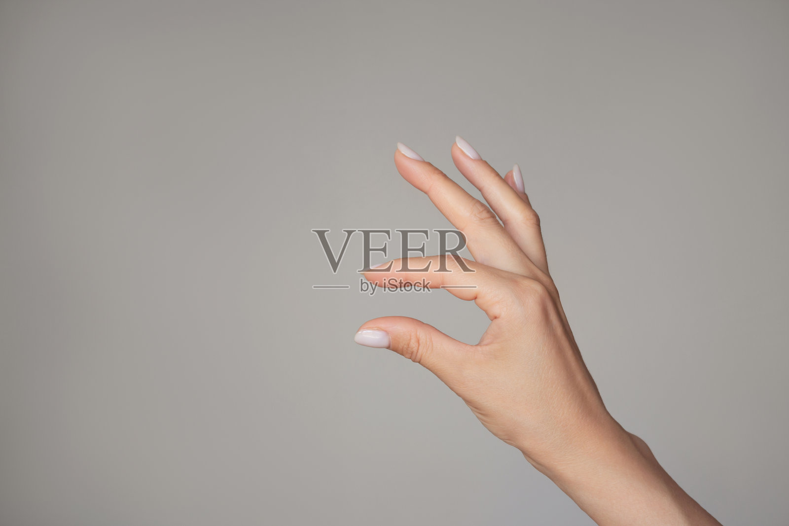 一只女性的手用两个手指夹着一个小物件或展示小尺寸。样机。空白副本空间照片摄影图片