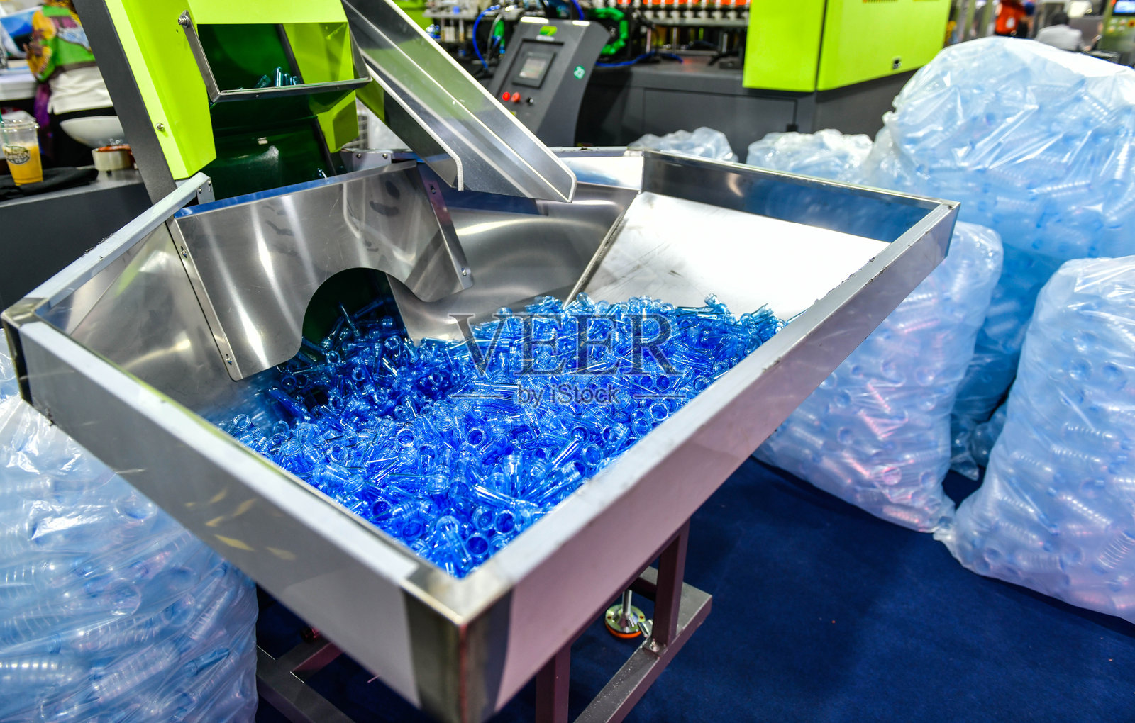 生产线上蓝色塑料瓶的制造过程，瓶子在吹塑之前。照片摄影图片