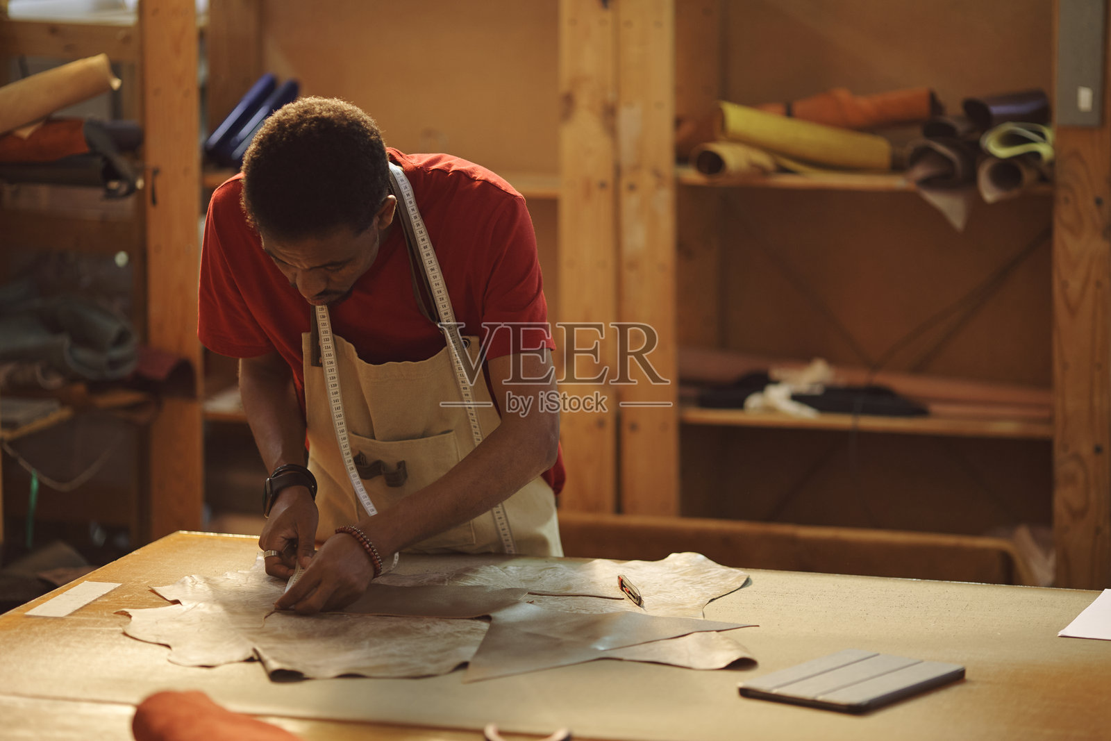 在材料环绕的工作坊中测量皮革照片摄影图片