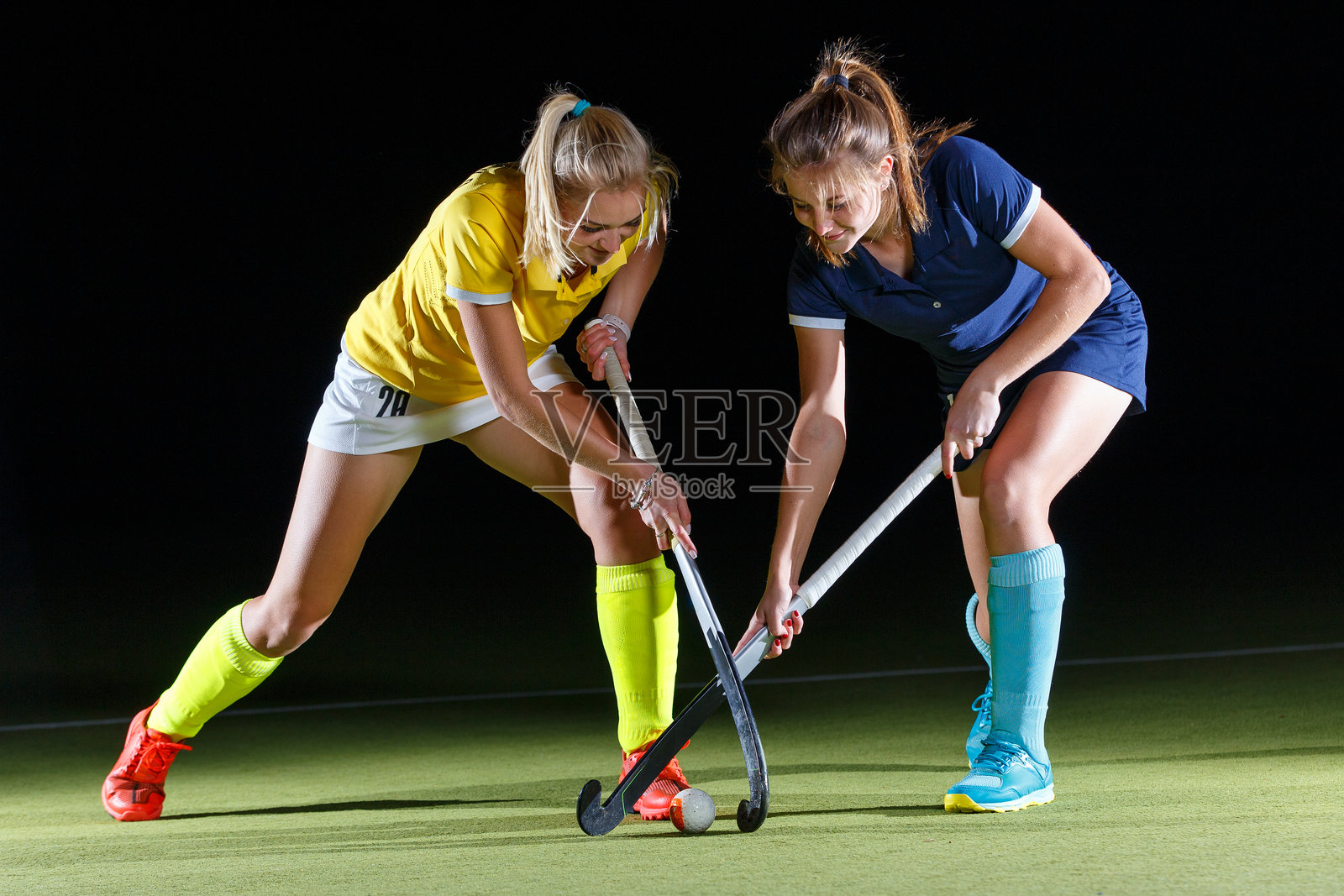 两名女曲棍球运动员在强烈对比光线下激烈比赛照片摄影图片