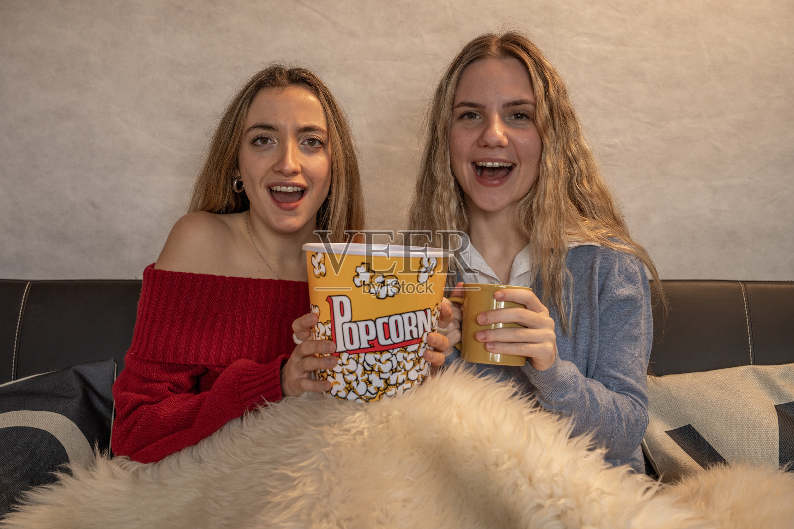 兴奋的年轻女性在家看电影时分享爆米花和饮料照片摄影图片