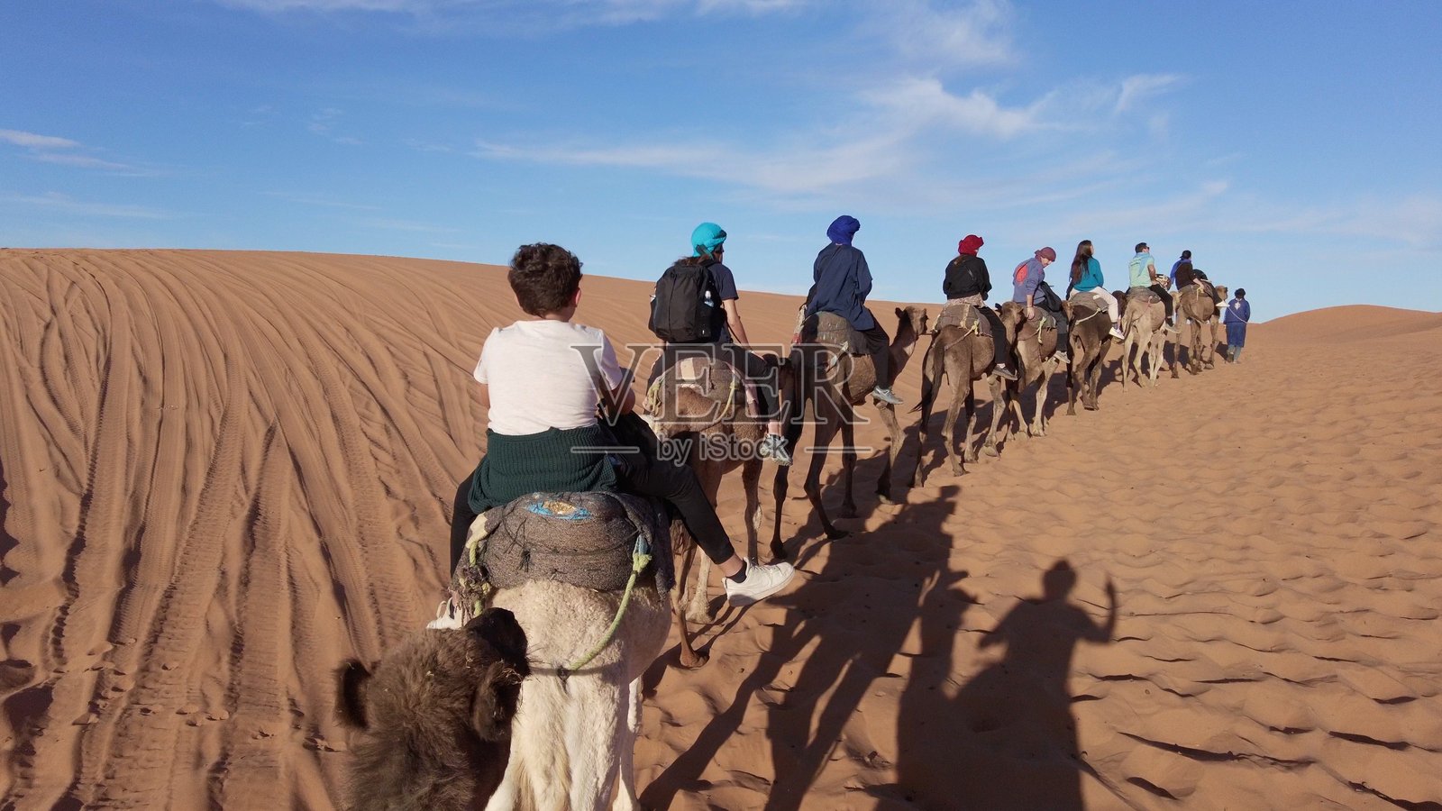 摩洛哥 沙漠中的骆驼队穿越非洲撒哈拉沙漠的沙丘,摩洛哥 - 梅尔祖卡 - 游客骑骆驼游览沙漠 - 冒险与自由的旅行,野生动物园 - 组织旅行照片摄影图片