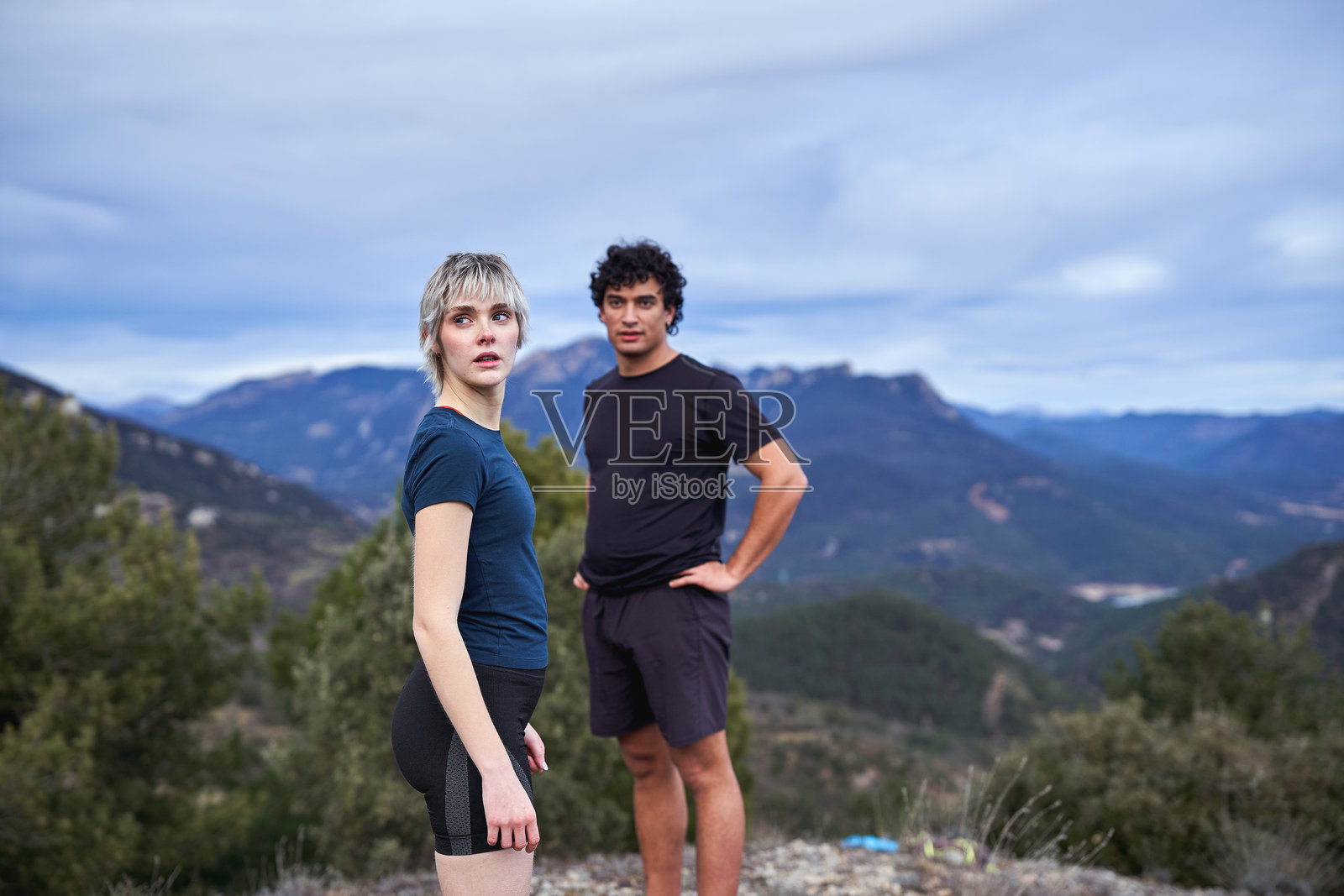 年轻的登山情侣站在山顶，欣赏美丽的风景照片摄影图片