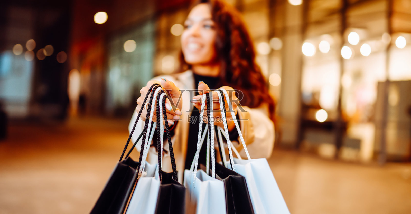 美丽的女性提着购物袋走在阳光明媚的欧洲街头。照片摄影图片