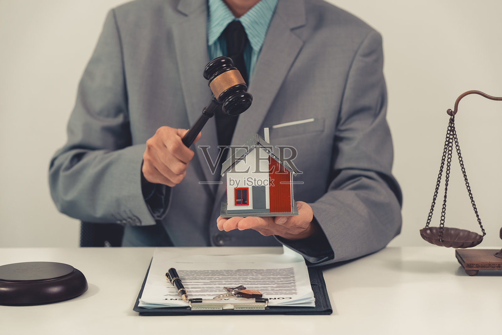 亚洲男性法官在使用笔记本电脑，手持法槌，涉及住房法庭、家庭住房概念、破产法和购房事务。照片摄影图片