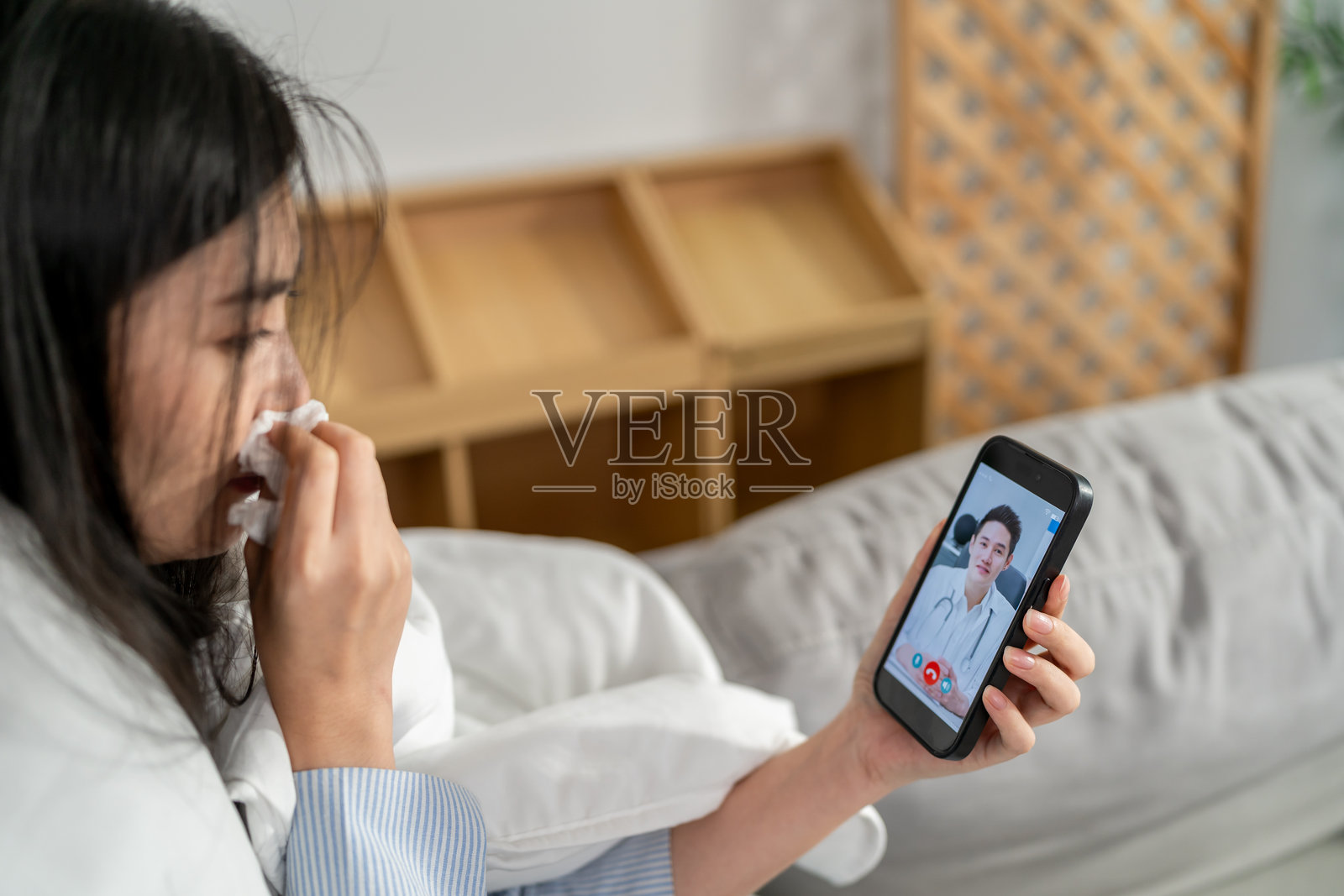 亚洲年轻女性患者与医生进行虚拟在线交流。吸引人的男医生通过视频通话为在家生病的女孩提供远程医疗咨询和诊断治疗。照片摄影图片