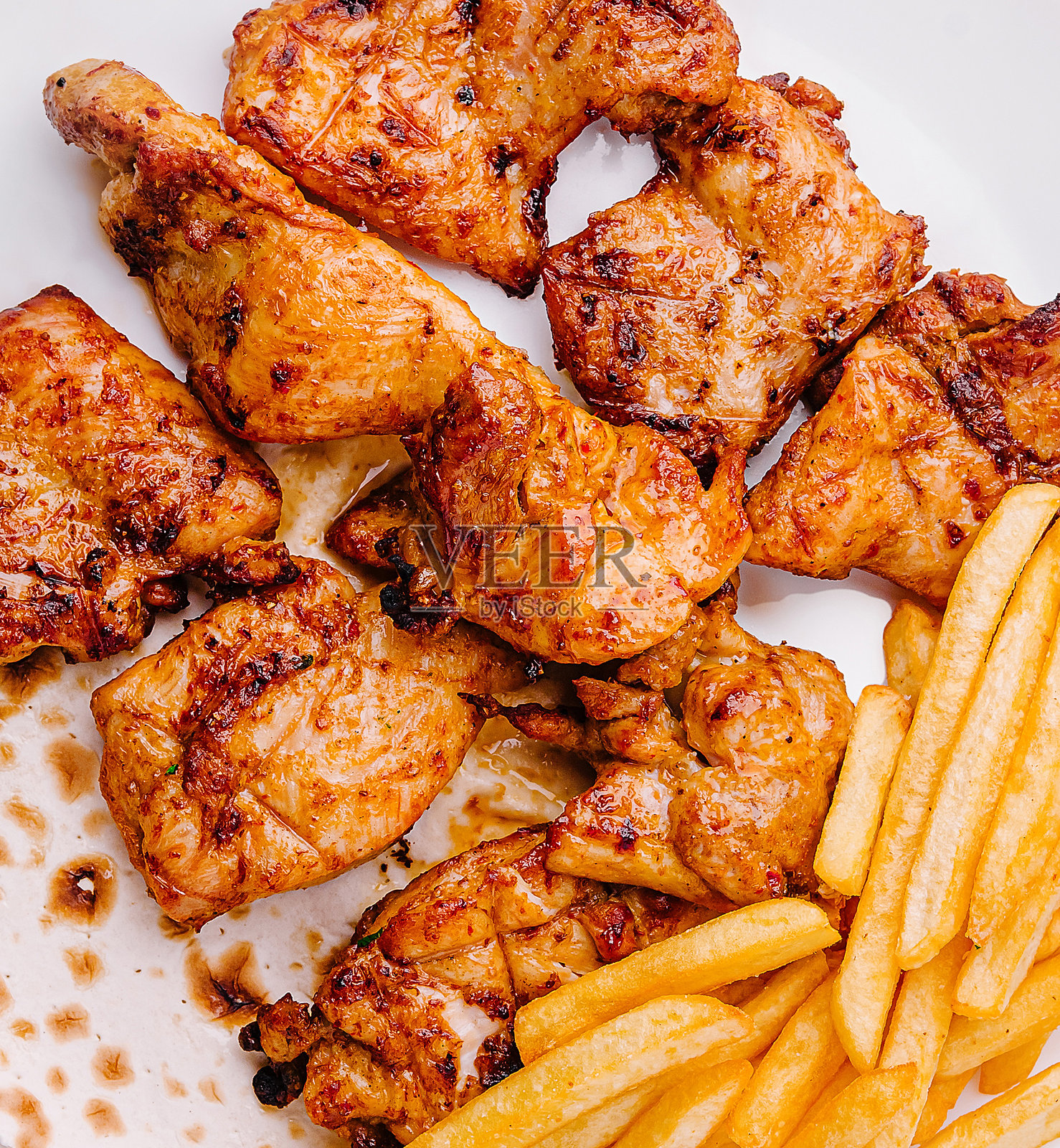 白色盘子上盛放着金黄色薯条和扁面包的烤鸡照片摄影图片