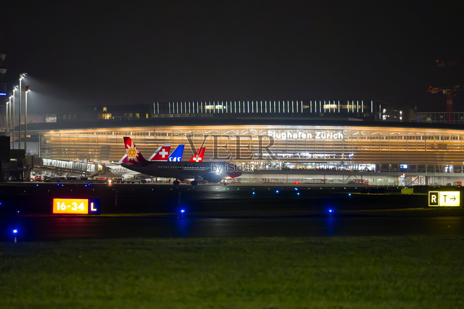 冬夜，Edelweiss Air的空客A320-214注册航班在瑞士苏黎世克洛滕机场滑行，展现出迷人的景色。照片摄影图片