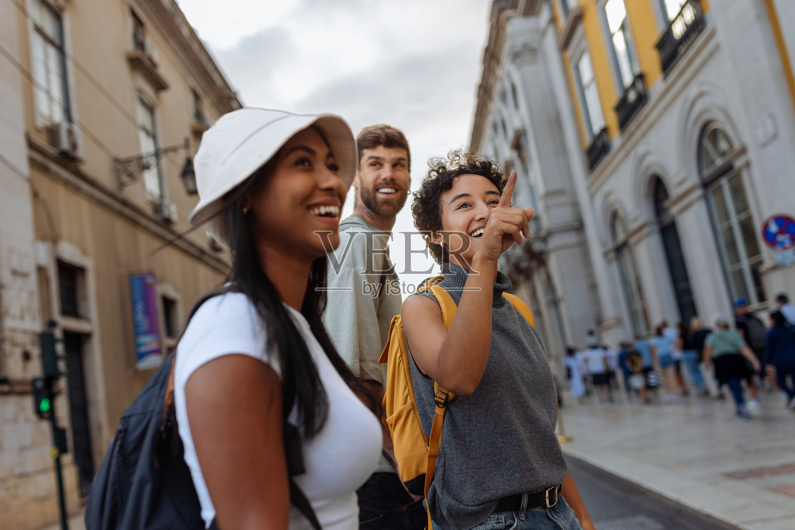 快乐的游客在城市中探索，一位女性指着地标。照片摄影图片