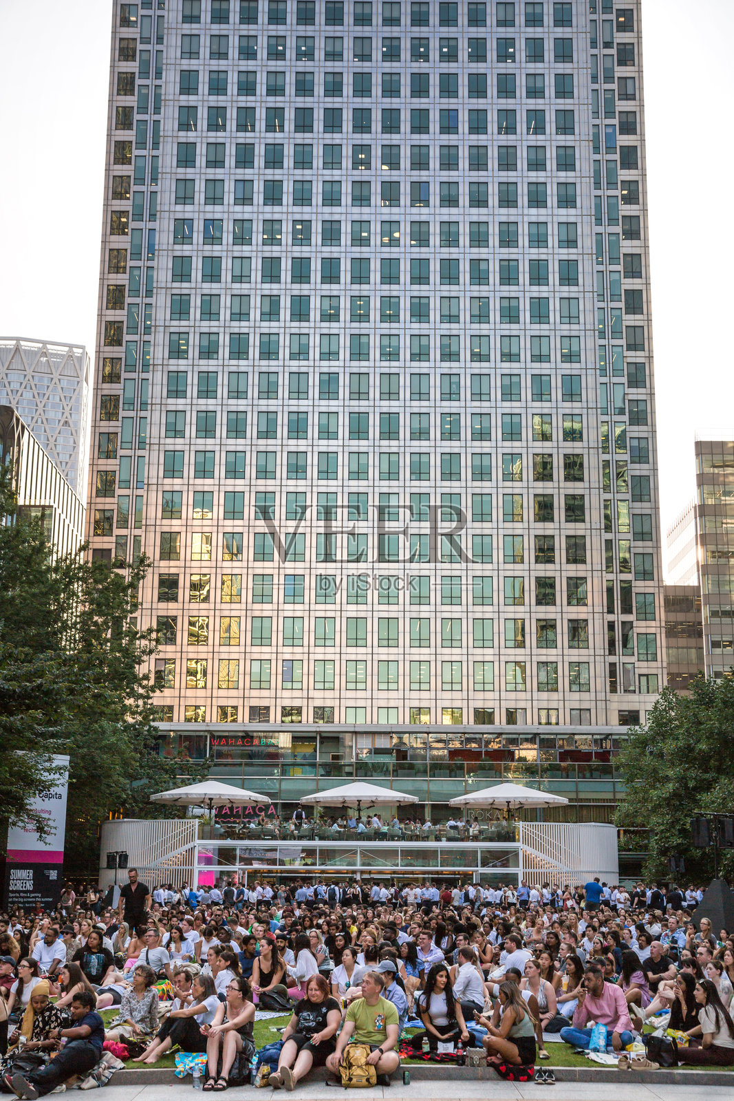 加拿大广场上人潮涌动，办公族在工作日结束后享受公共活动。人们在金丝雀码头观看电影，喝饮料，享受野餐。照片摄影图片