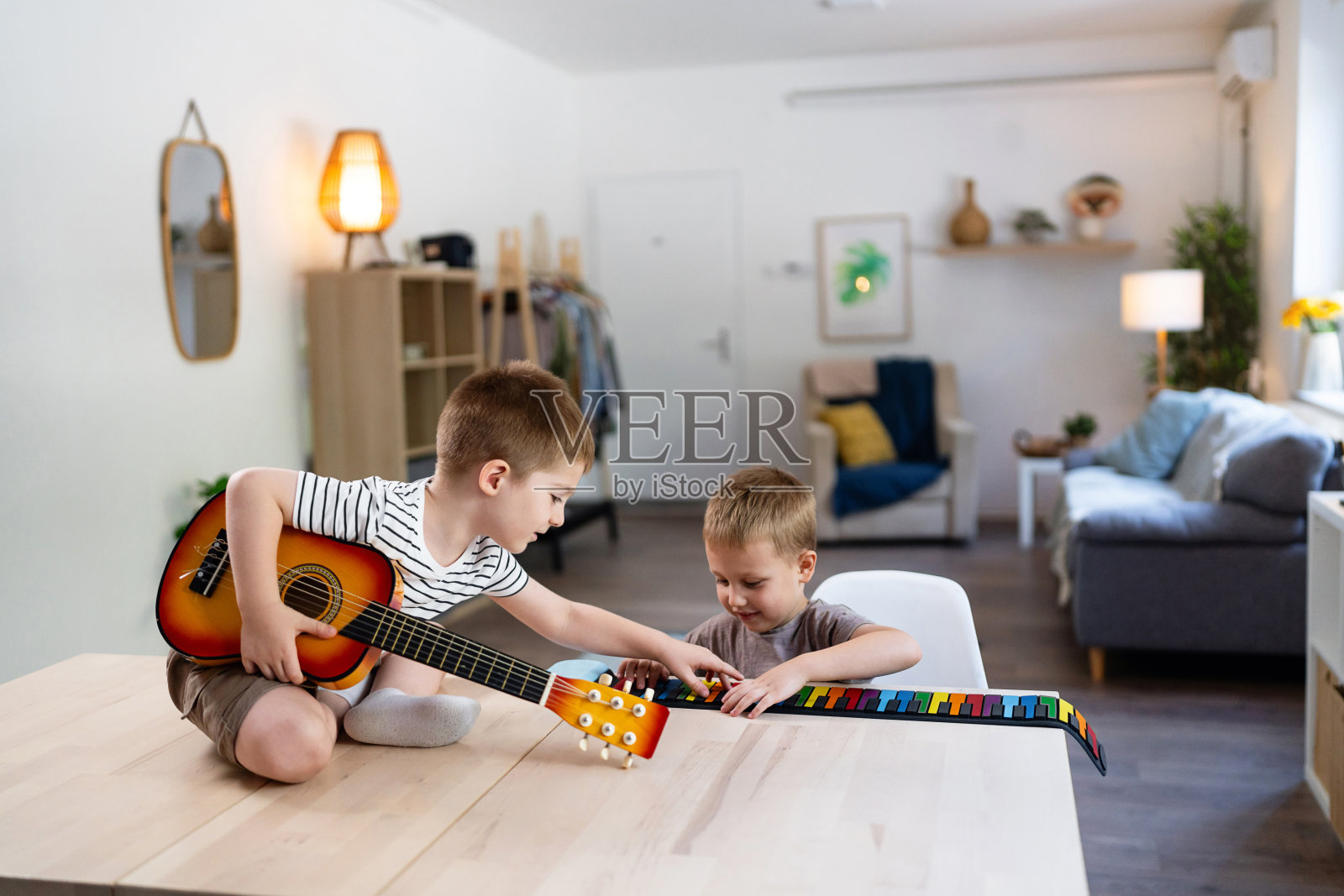 两个兄弟在享受音乐，弹奏吉他和五彩斑斓的键盘照片摄影图片