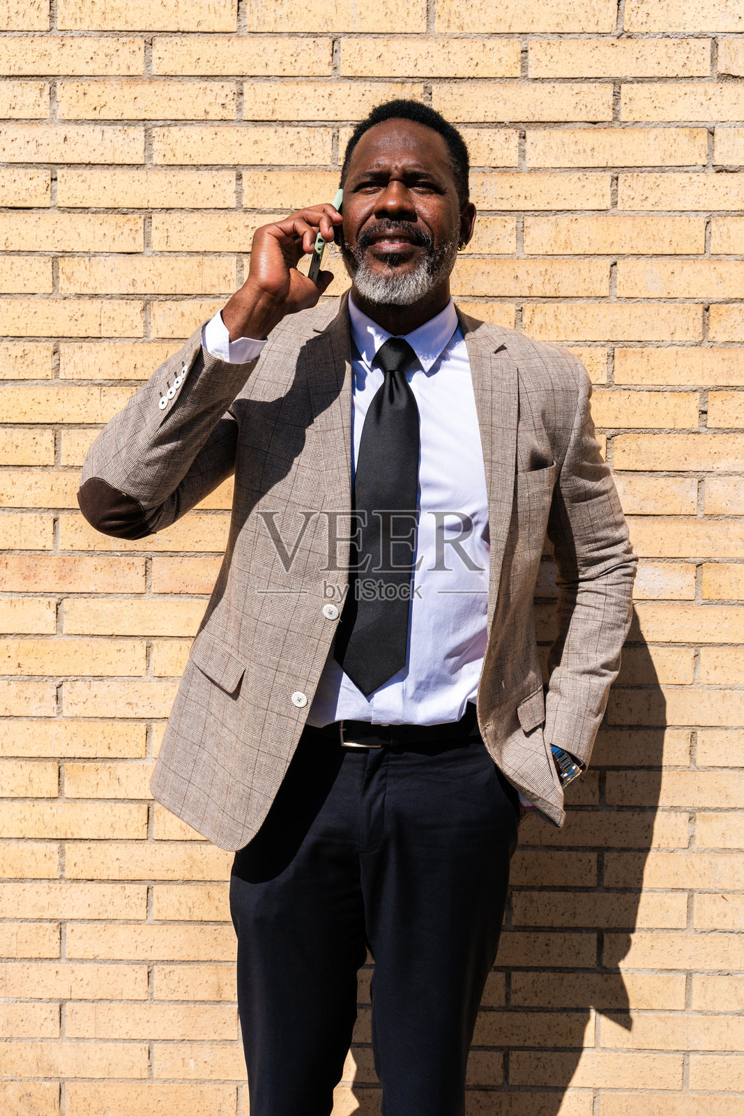 成熟的黑人商人穿着优雅的西装在城市中漫步照片摄影图片