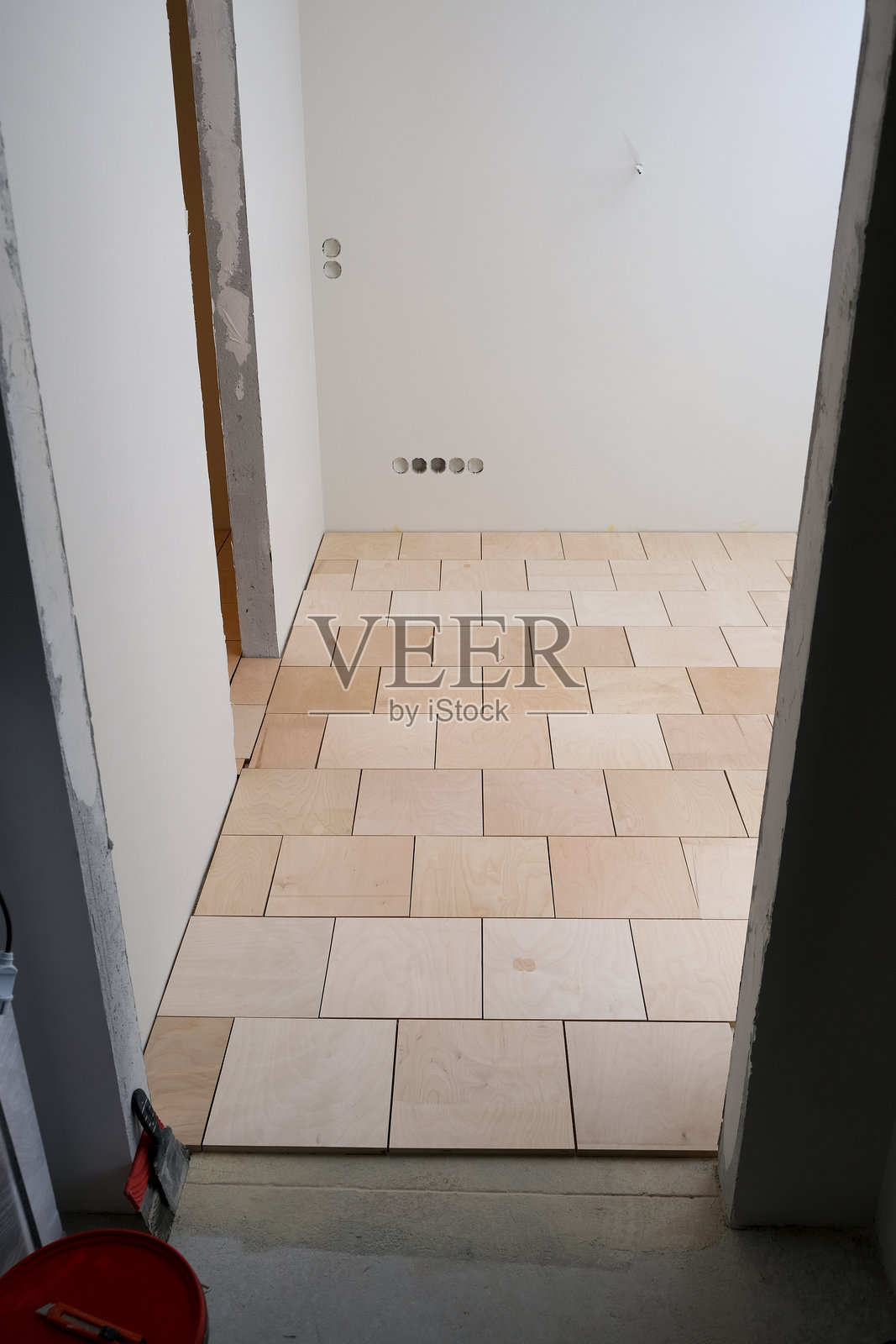 公寓翻新。地面铺满胶合板。为铺设成品地面覆盖物（如木地板或复合地板）准备基础。维修工作。墙壁上安装电源插座。照片摄影图片