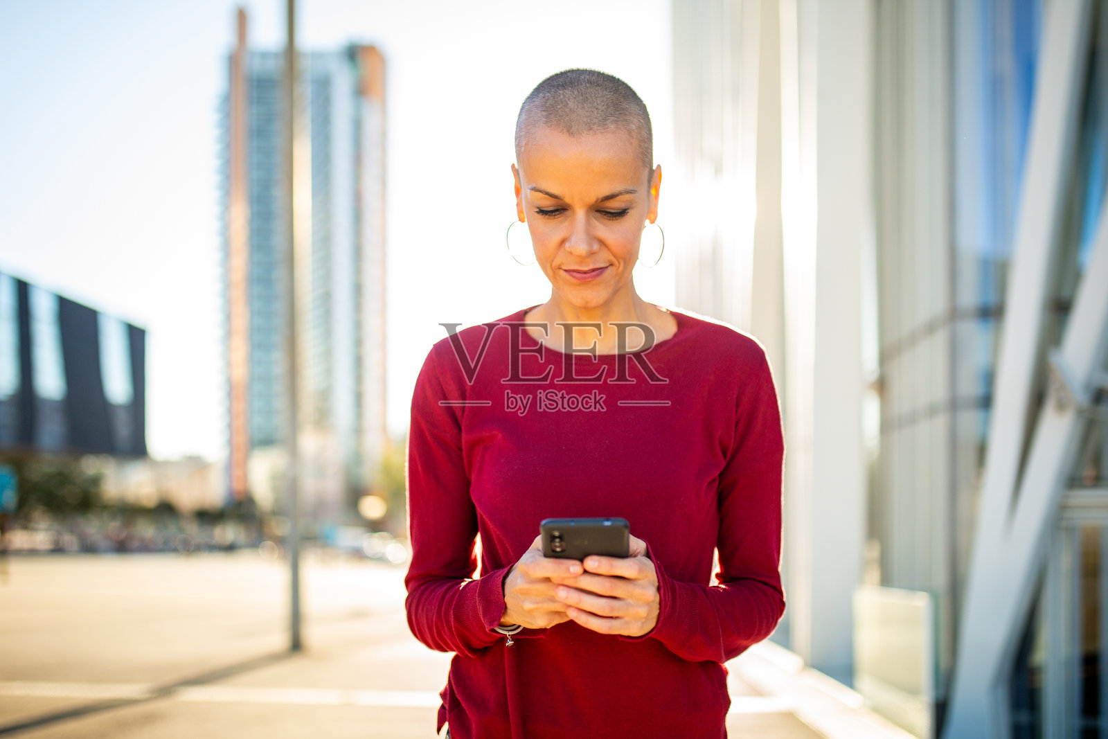 女人在城市中拿着手机并注视着它照片摄影图片