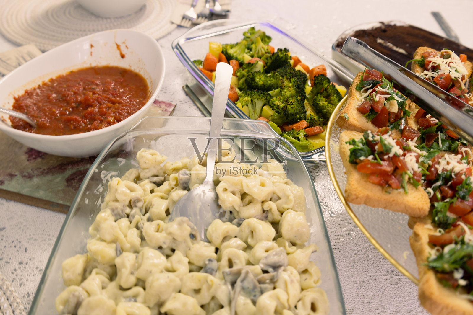 意大利自制盛宴，配有奶油意大利饺子、意式面包片和烤蔬菜照片摄影图片