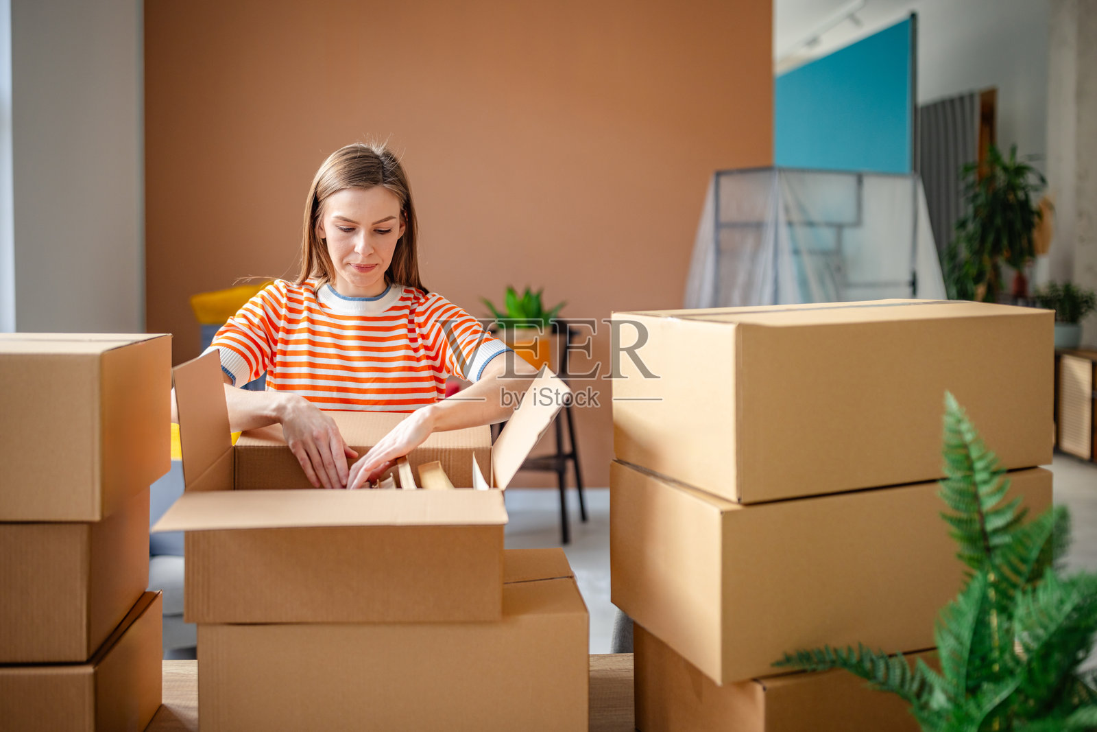 年轻女性在新公寓中愉快地拆箱，拥抱新的房屋拥有生活。照片摄影图片