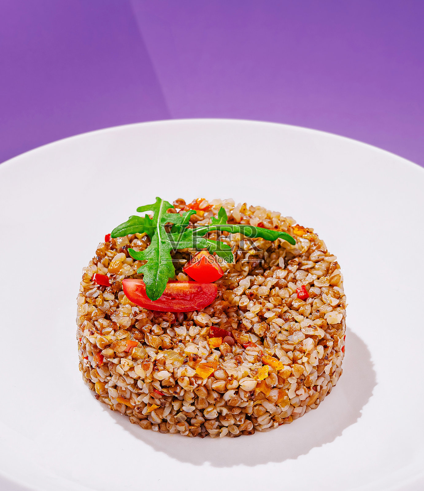 白盘上盛放的粗麦沙拉，背景为鲜艳的紫色，突显新鲜食材。照片摄影图片