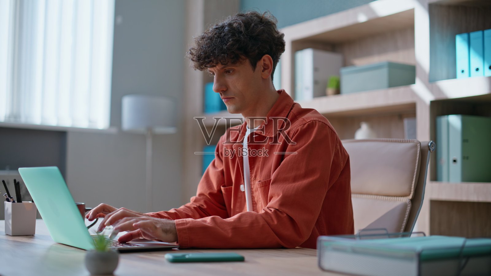 快乐的员工在公司办公室里阅读短信，专注于电脑工作。照片摄影图片