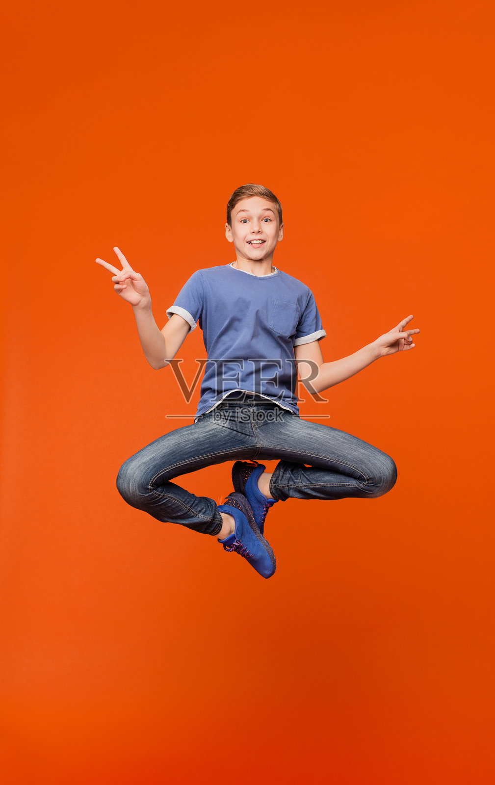 可爱男孩跳跃并做出和平手势照片摄影图片