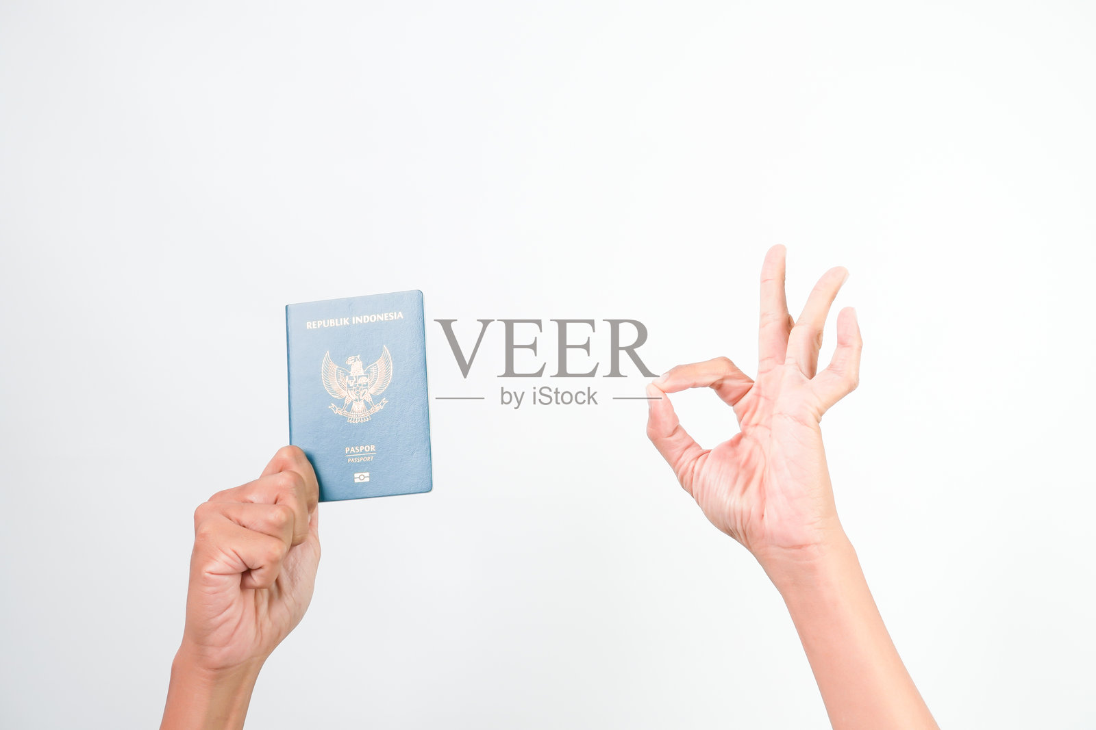 印尼男子的手握着印尼电子护照，背景为白色。照片摄影图片