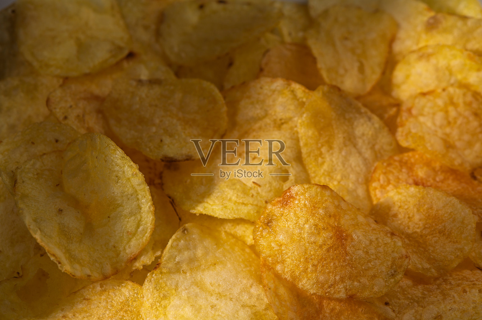 在温暖灯光下闪闪发光的脆薯片，营造出舒适的零食氛围照片摄影图片