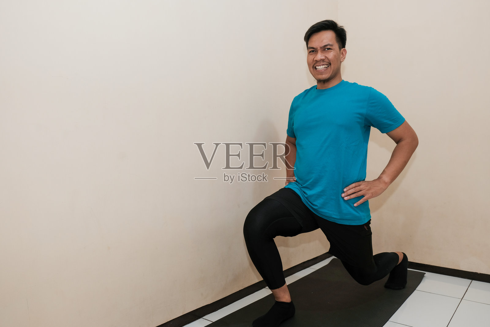 微笑的东南亚男子在家中锻炼，保持健康的生活方式照片摄影图片